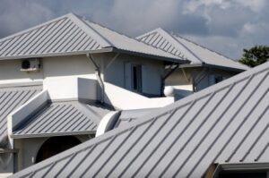 Series of grey gabled raised seam metal roofs on white houses