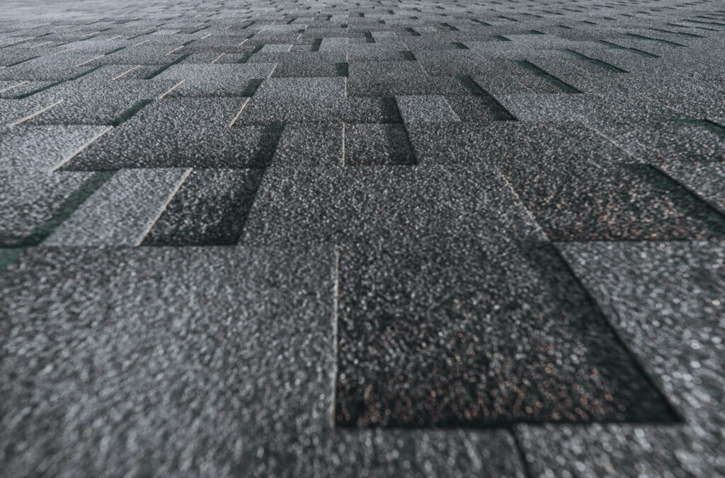 Close-up view of dark gray rectangular roof shingles arranged in a geometric, overlapping pattern, creating a textured surface that extends toward the background—ideal for New Orleans Shingle Roofing projects.